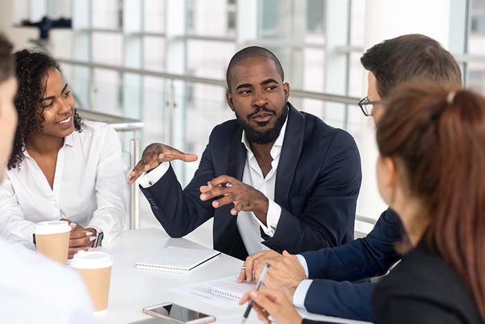 Young black businessman leading a corporate team at a table
